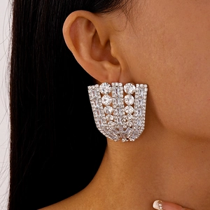 Macro close-up of geometric fan-shaped rhinestone earrings worn on a female model's ear