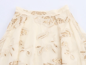 Detailed close-up of mesh fabric with floral embroidery and golden sequins on the waistband