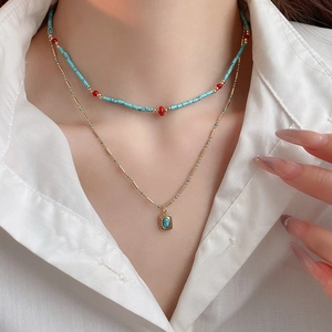 Detail of bohemian layered necklace with turquoise beads and gold pendant on model