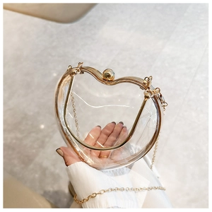 Detailed close-up of a transparent heart-shaped acrylic bag with gold metal frame and chain