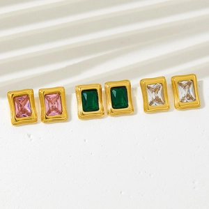 Detail of three pairs of gold-plated rectangular zircon earrings in pink, emerald, and clear
