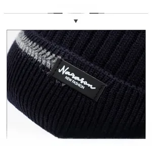 Detail of ribbed knit texture on navy beanie with Narason fashion label and gray stripe
