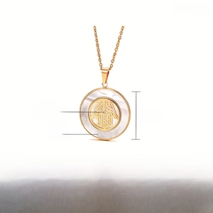 Detail of gold stainless steel Hamsa necklace with white shell inlay and crystal