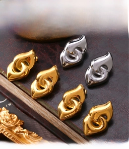 Detail of PVD electroplated 18K gold and silver twist knot earrings on leather texture