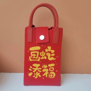 Detail of red knit phone bag featuring yellow Chinese characters and silver button