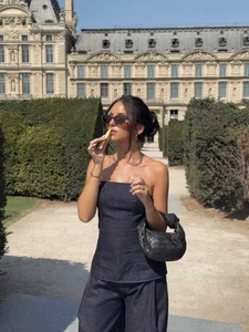 Dettaglio del bustino in denim nero e dei pantaloni ampi coordinati con borsa intrecciata