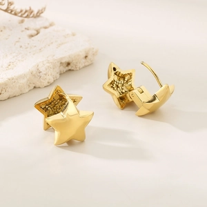 Macro view of gold minimalist double-layered star hoop earrings on a textured stone base
