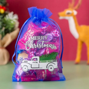 Close-up of blue organza drawstring gift bag with Merry Christmas truck print and candies