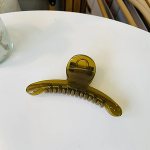 Close-up of translucent olive green resin hair claw clip with durable metal spring mechanism