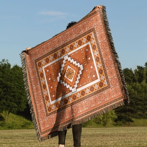 Close-up of bohemian knit blanket with orange geometric patterns and woven tassels