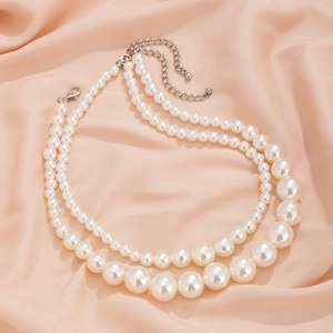Detail of double-layer faux pearl necklace with silver lobster clasp on pink silk