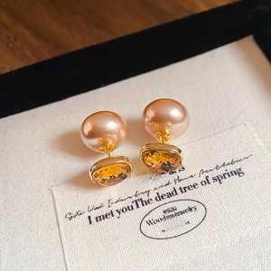 Macro detail of square yellow gemstone and pink pearl gold-plated earrings