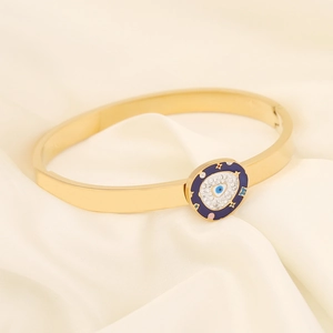 Close-up of golden evil eye bracelet with rhinestones on a white silk background