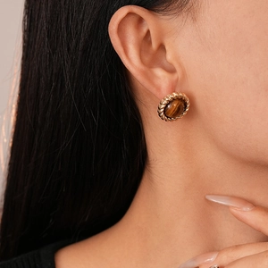 Gros plan de boucles d'oreilles vintage rondes dorées avec pierre œil de tigre brune