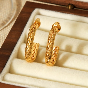 Detailed close-up of 18k gold-plated C-shaped twisted earrings in a wooden jewelry box