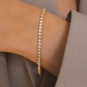 Close-up of gold tennis bracelet with clear round crystals on a model wrist