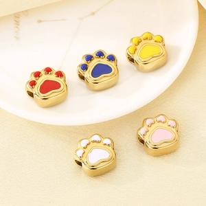 Macro detail of golden animal paw charms with colorful enamel inlay for DIY jewelry