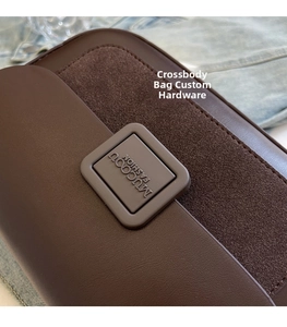 Detail of dark brown leather crossbody bag featuring suede textures and custom hardware