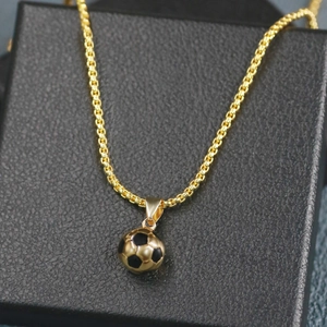 Close-up of golden soccer ball pendant on black leather box with metallic chain