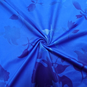 Gros plan sur un tissu bleu à imprimé floral avec silhouettes et texture soyeuse
