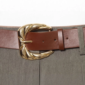 Ceinture chic en cuir marron avec boucle dorée sur un pantalon décontracté gris à jambe droite