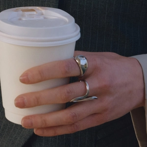 Close-up of silver steel rings with zircon on model holding a coffee cup