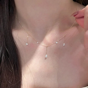Close-up of golden tassel necklace with sparkling teardrop zircon pendants on model