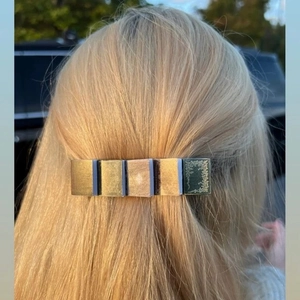 Detailed view of a miniature book hair clip in gold finish worn on blonde hair