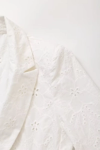 Detail of white cotton eyelet embroidery and notch lapel on the tailored blazer