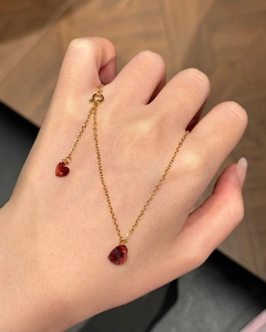 Macro view of dainty gold necklace with two vibrant red heart-shaped crystal pendants