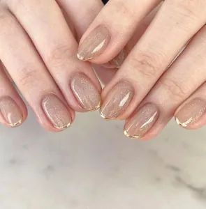 Detailed view of nude glitter french nails with elegant gold rim on short oval shape