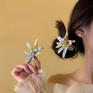 Detail of starfish and blue flower hair claw clip with pearls on hair and in hand
