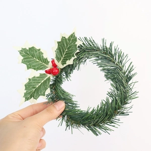 Close-up of a mini Christmas candle ring with pine needles and red holly berries
