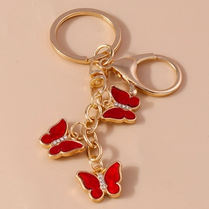 Golden butterfly keychain with three red enamel pendants and sparkling rhinestones