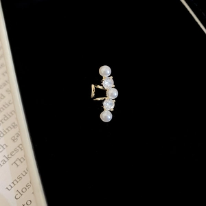 Macro d'une manchette d'oreille dorée avec perles verticales et zircons étincelants