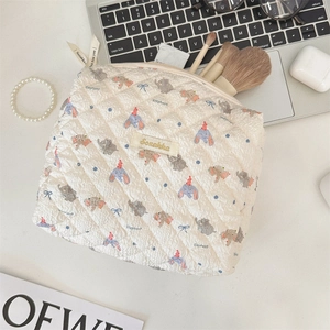 Detailed top view of a quilted makeup bag featuring blue elephant and bow prints