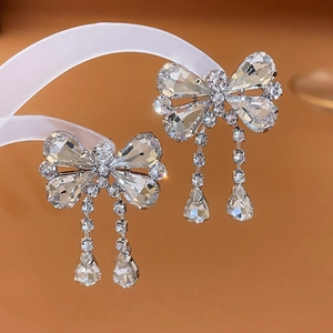 Macro detail of silver bow earrings with sparkling crystals and elegant fringe drops
