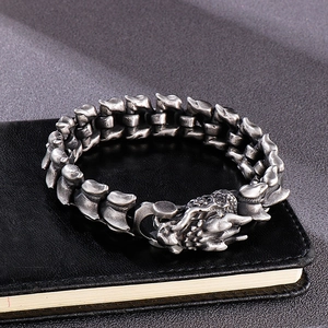 Close-up of retro dragon scale chain bracelet with ornate clasp on black leather