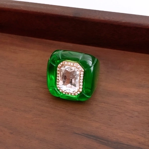 Macro shot of green resin ring with a rectangular crystal centerpiece and gold accents