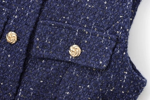 Detail of dark blue tweed fabric with sequins and spiral golden metal buttons