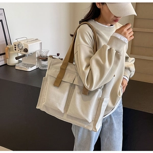 Close-up of beige canvas tote bag with brown straps and large front pockets for storage