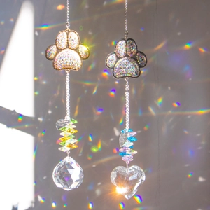 Detail of paw-shaped crystal suncatchers casting rainbow reflections on a wall