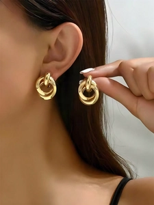 Detailed close-up of golden triple-interlocking hoop earrings on a female model