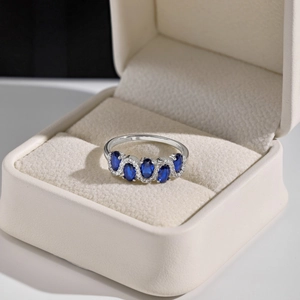 Macro shot of S925 sterling silver ring with blue oval gems in a beige jewelry box