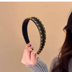 Detail showing elegant black fabric headband with integrated golden metal chain texture
