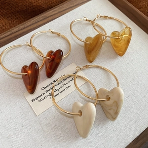 Detailed shot of three pairs of heart acrylic hoop earrings with golden marble resin texture