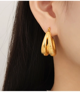 Detail of gold-plated U-shaped earrings featuring a sleek polished and textured double hoop design