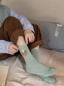 Close-up of light green cotton crew socks with bear embroidery and colorful flecks