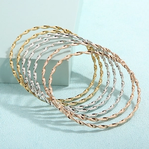Detailaufnahme der gedrehten Seilstruktur von Armreifen in Gold, Silber und Roségold