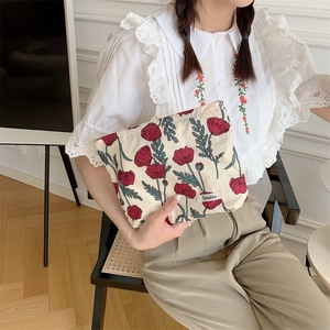 Lifestyle shot of a woman holding a floral cotton makeup bag with red poppy prints